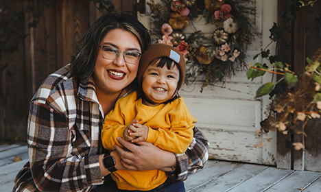 an Indigneous woman smiling with a young boy.