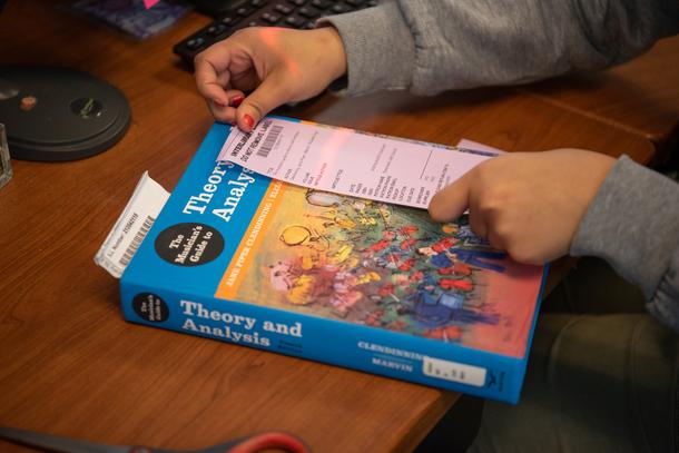 Samrah places an interlibrary loan sticker on a book