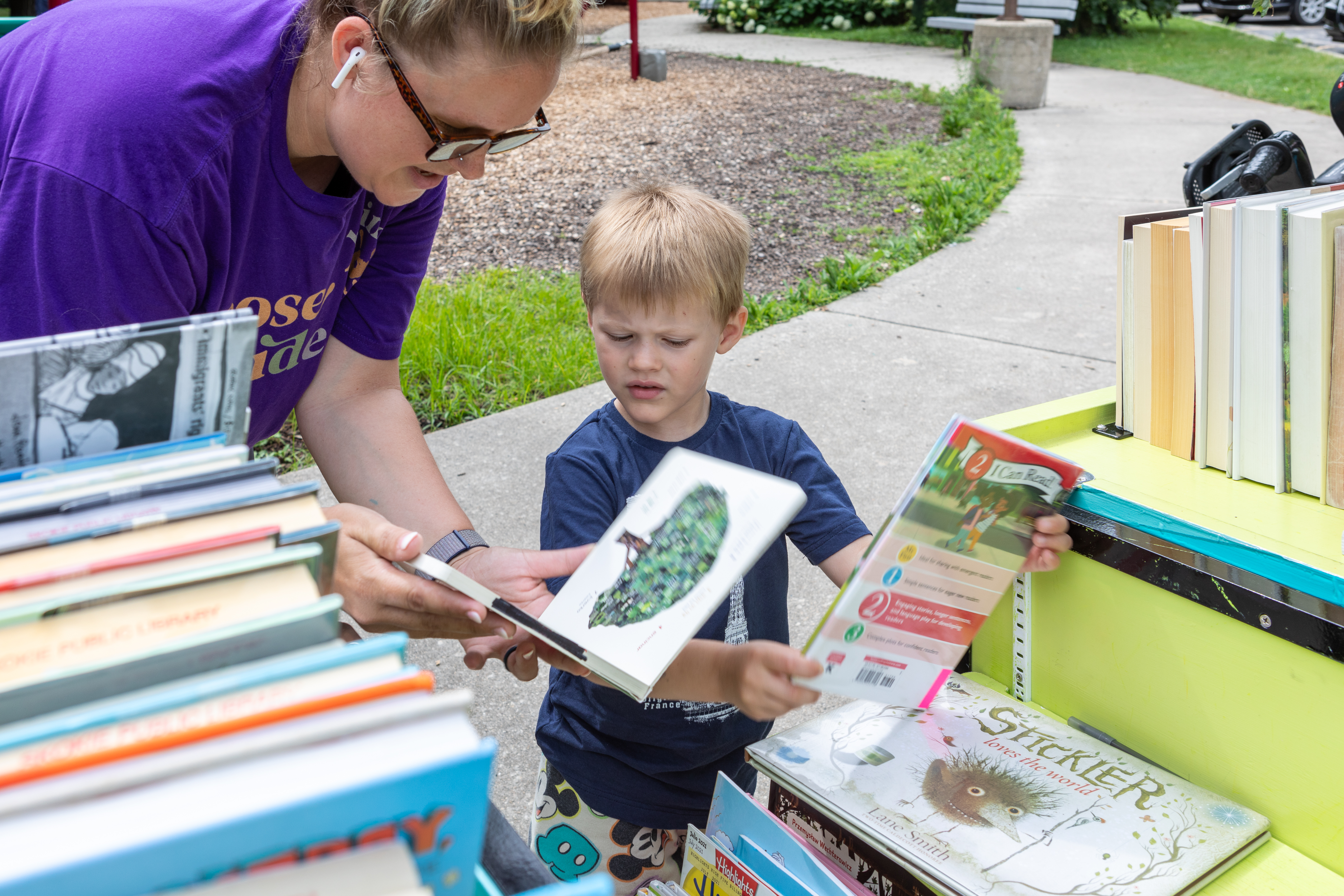 an adult woman and young boy looking at books on the book bike