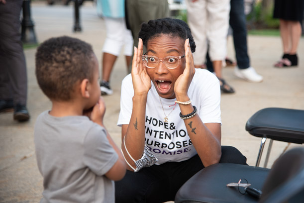 A woman plays peek-a-boo with a young child during the opening ceremonies of Skokie's Juneteenth Celebration.