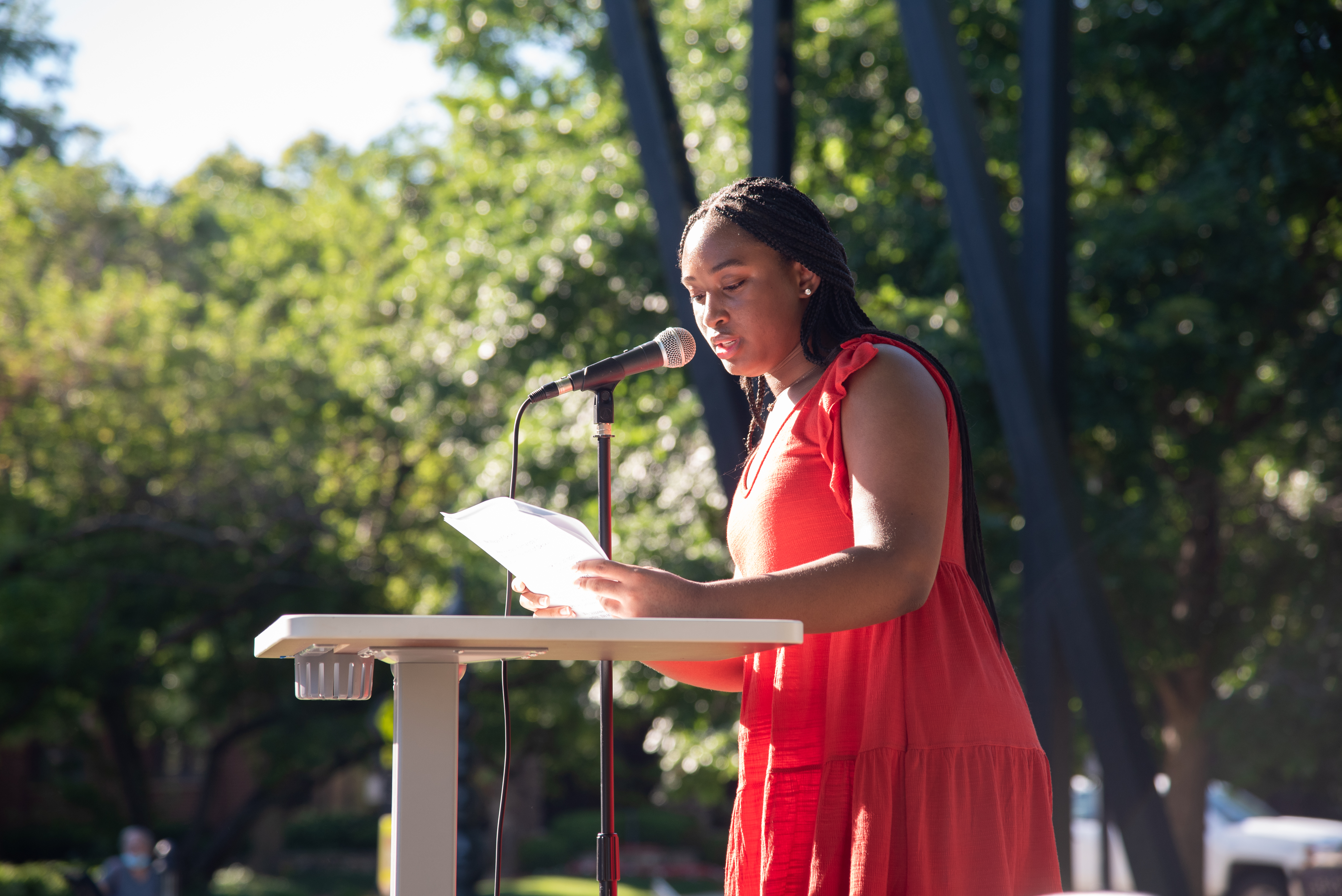 woman standing on a stage speaking into a microphone