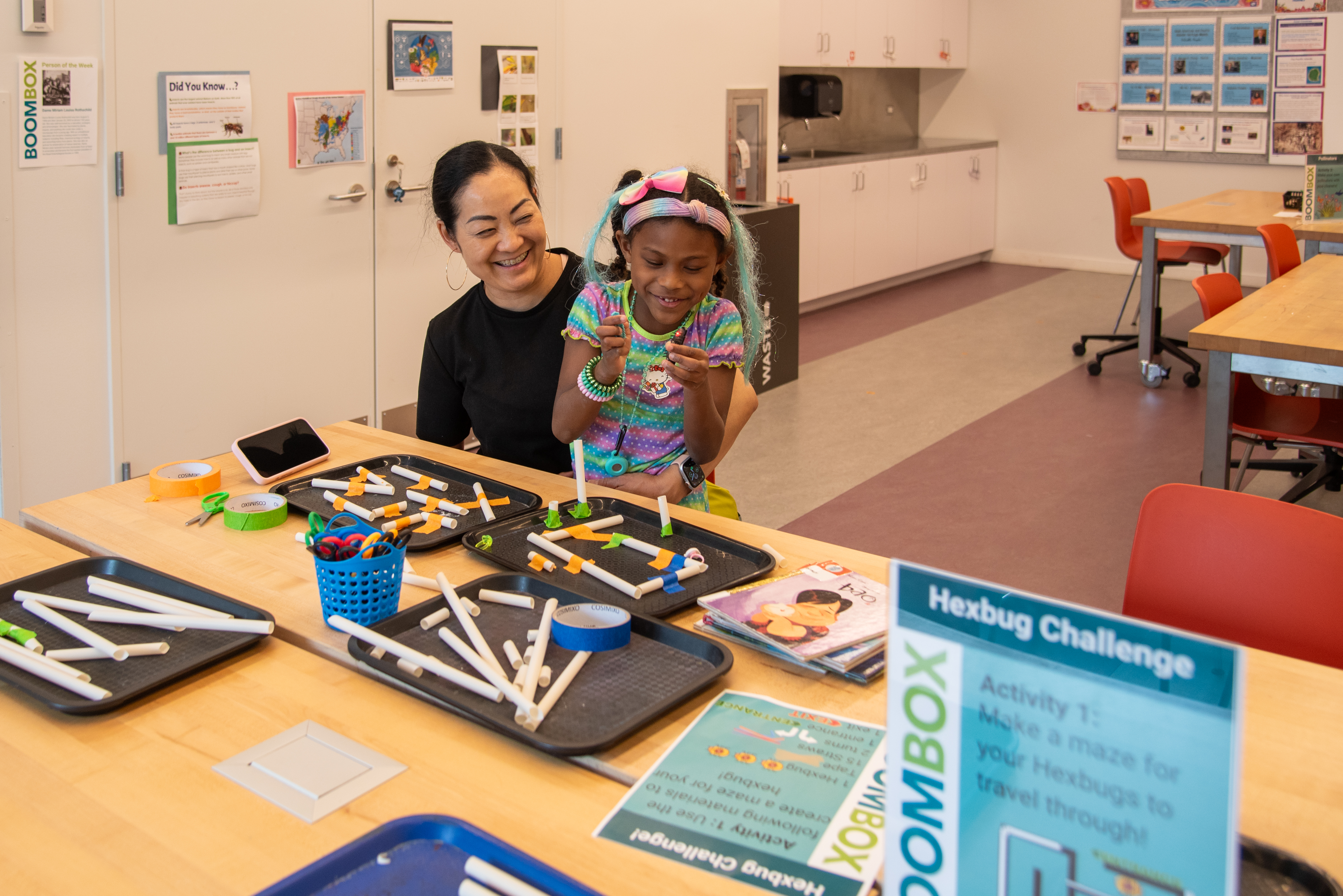 a woman and child are smiling while experimenting in the BOOMbox